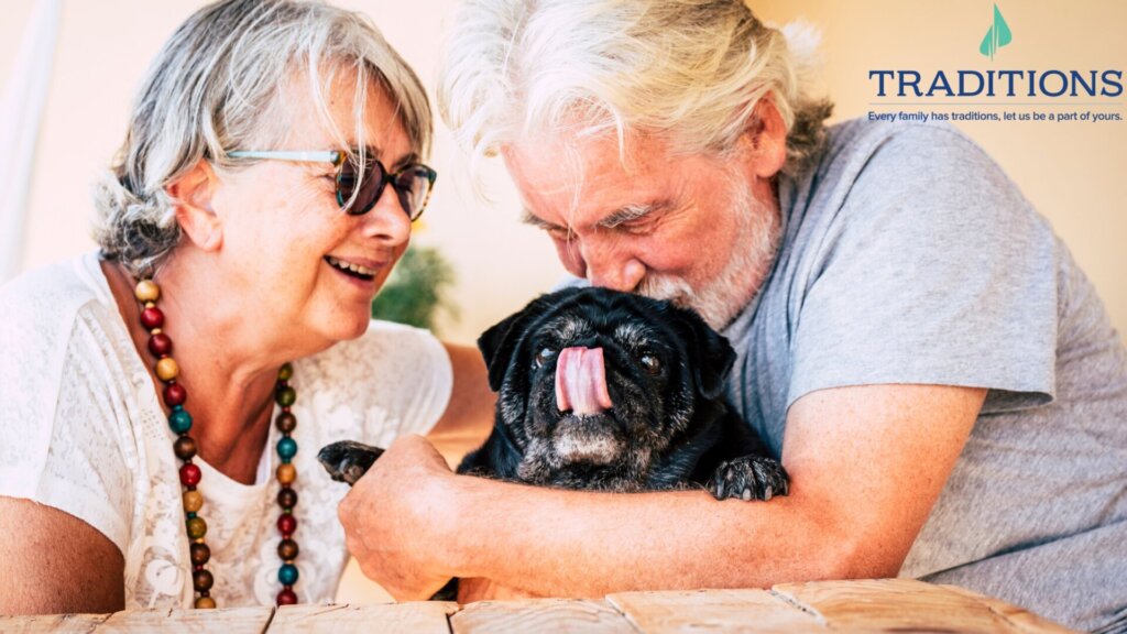 Senior man and senior woman in their Traditions at North Bend apartment holding their pet pug and kissing it