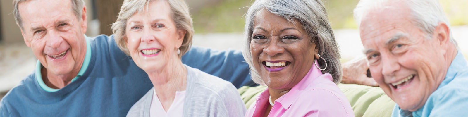 Senior men and women sitting outside together while smiling